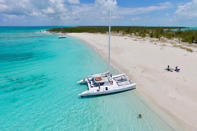 A sailing catamaran anchored off a white-sand spit in turquoise water