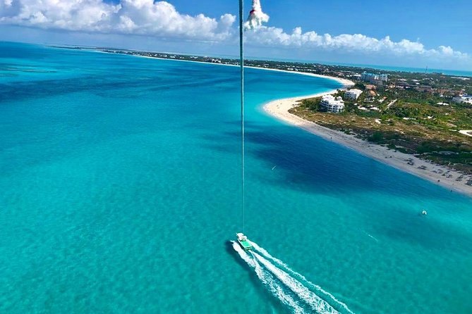 A long white beach curving along turquoise water, seen from high above