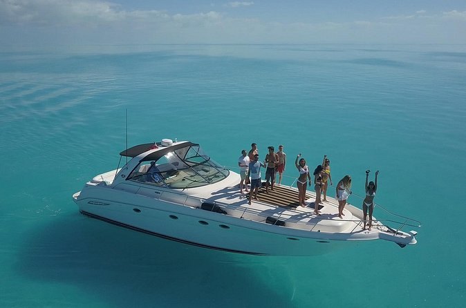 A motor yacht at anchor in turquoise water, swimmers off the stern