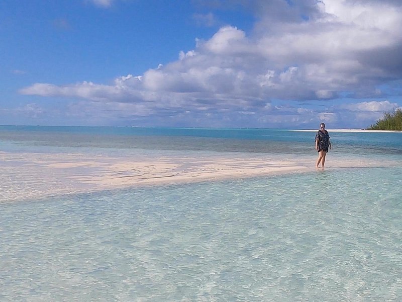 A wide sandbar in clear shallow water, one figure far out on the flats