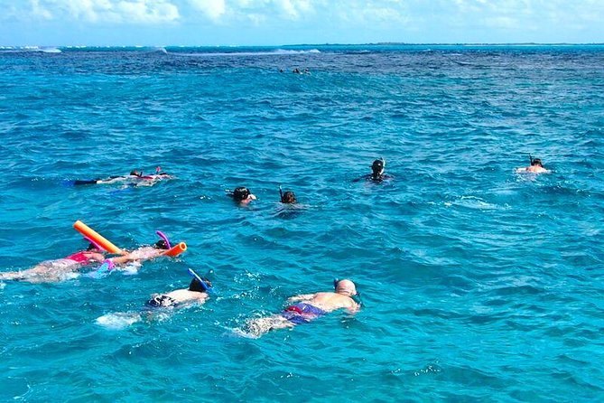 Snorkelers spread over a reef in blue water, seen from above